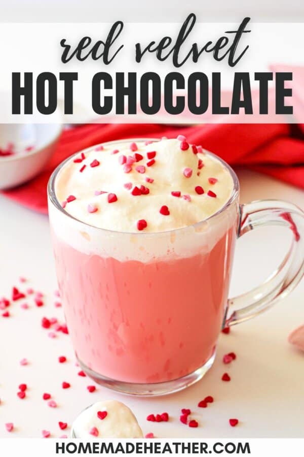 Red velvet hot chocolate in a clear mug topped with whipped cream and sprinkles.