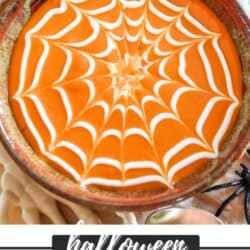 Tomato soup with sour cream in a spiderweb shape on top.
