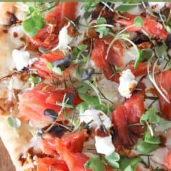 A flatbread topped with smoked salmon, mustard greens, goat cheese and balsamic vinegar.