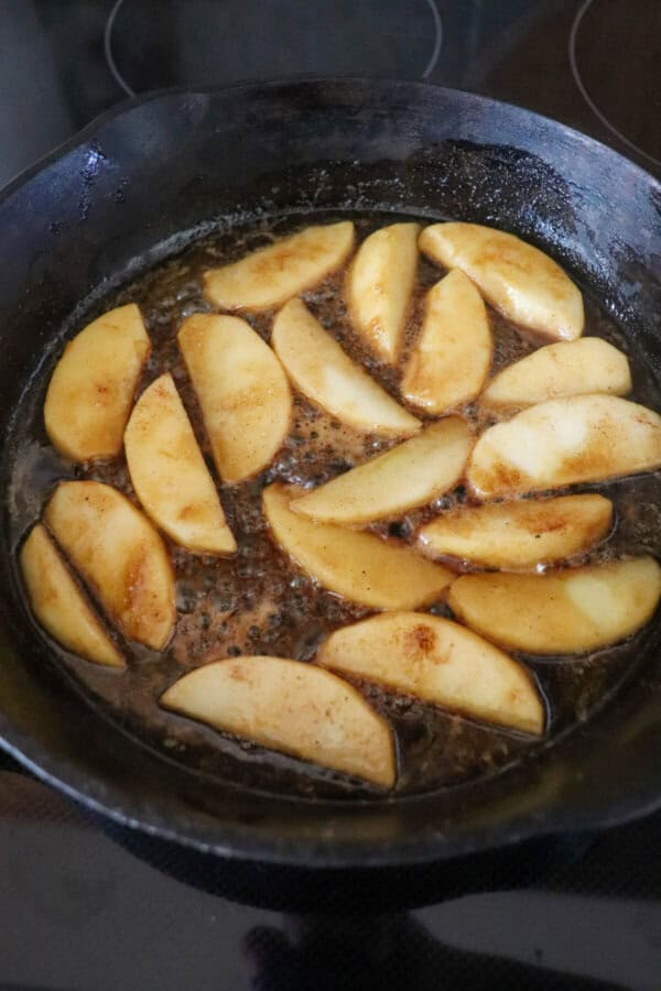 Apples cooking in a cast iron skillet.