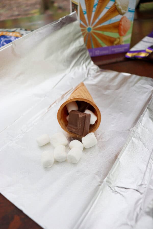 Cone filled with marshmallows and chocolate on a piece of foil.