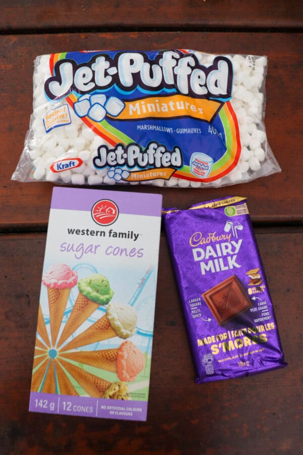 Ingredients for s'mores cones on a wooden picnic table.