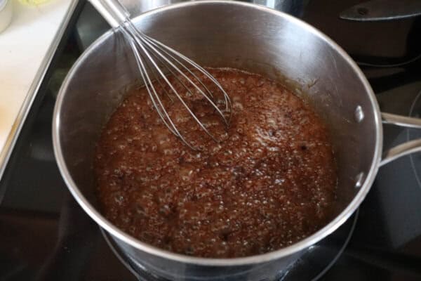 Maple brown sugar sauce boiling in a sauce pan with a whisk in it.