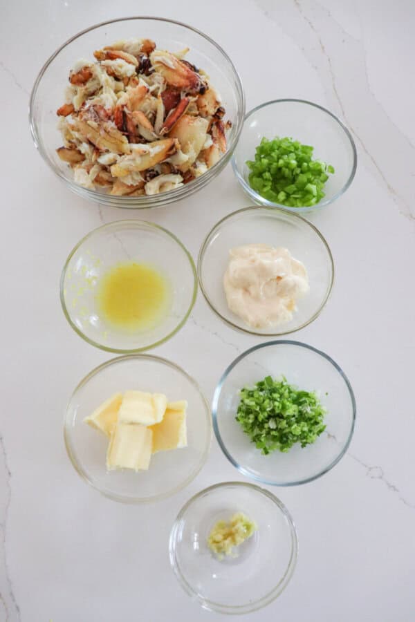 Crab roll ingredients in clear glass bowls on a white counter.