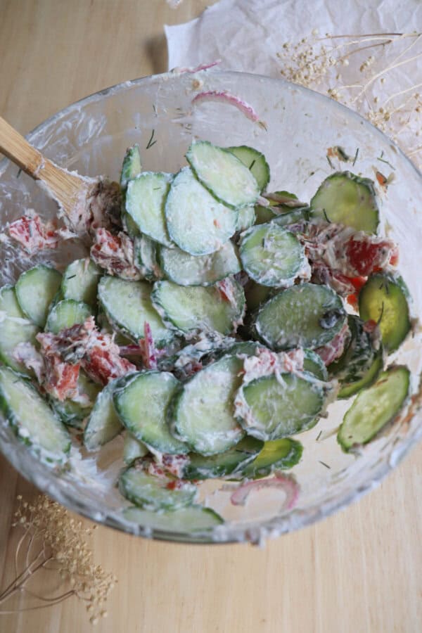 Cucumber smoked salmon salad mixed in a clear glass bowl.