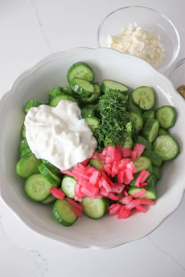 Tzatziki cucumber salad ingredients in a white mixing bowl.
