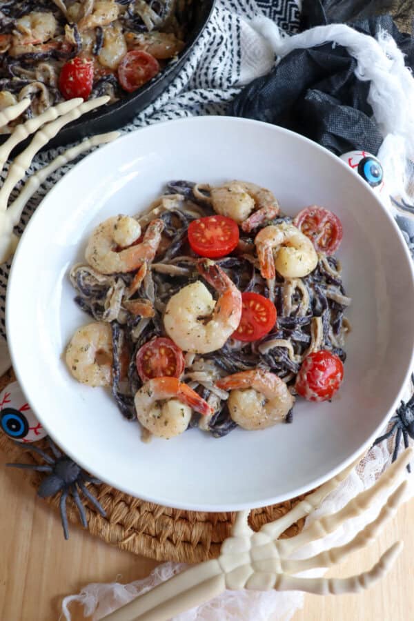 Purple and white linguine noodles in a cream sauce topped with shrimp and cherry tomatoes.
