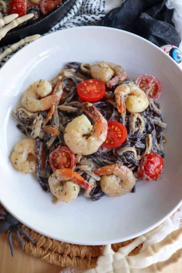 Purple and white linguine noodles in a cream sauce topped with shrimp and cherry tomatoes.