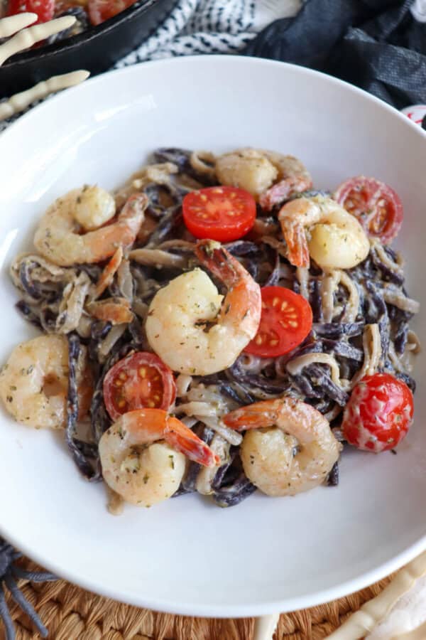 Purple and white linguine noodles in a cream sauce topped with shrimp and cherry tomatoes.