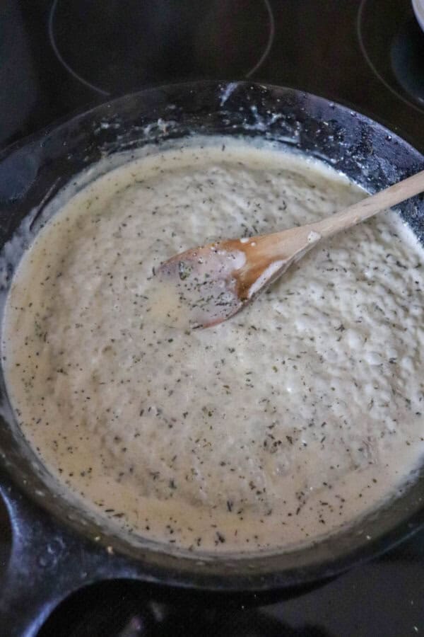 Cream sauce bubbling in a cast iron skillet.