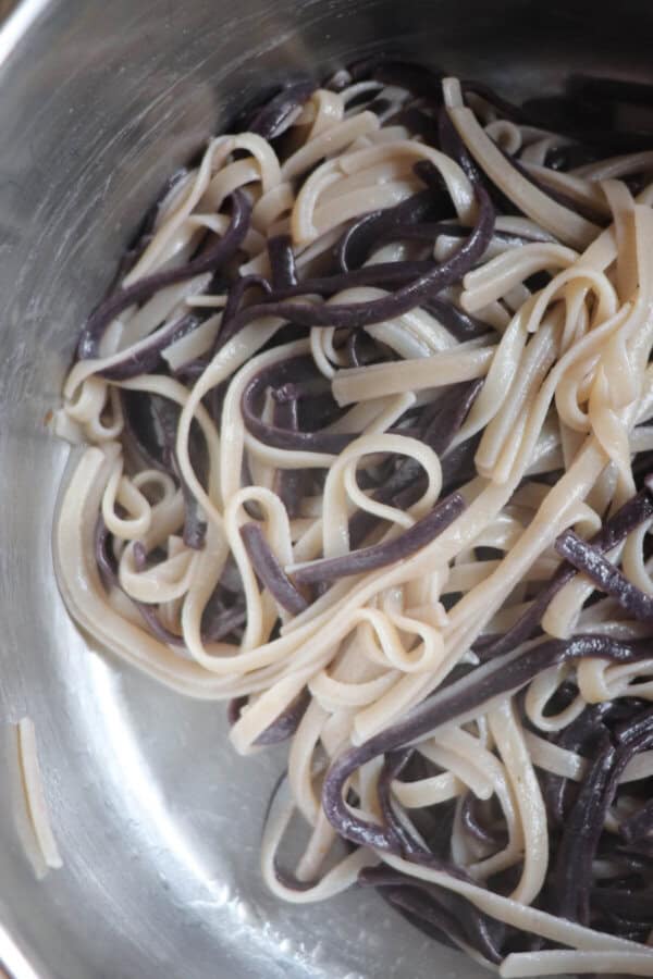 Black and white linguini noodles cooked and resting in a pot.