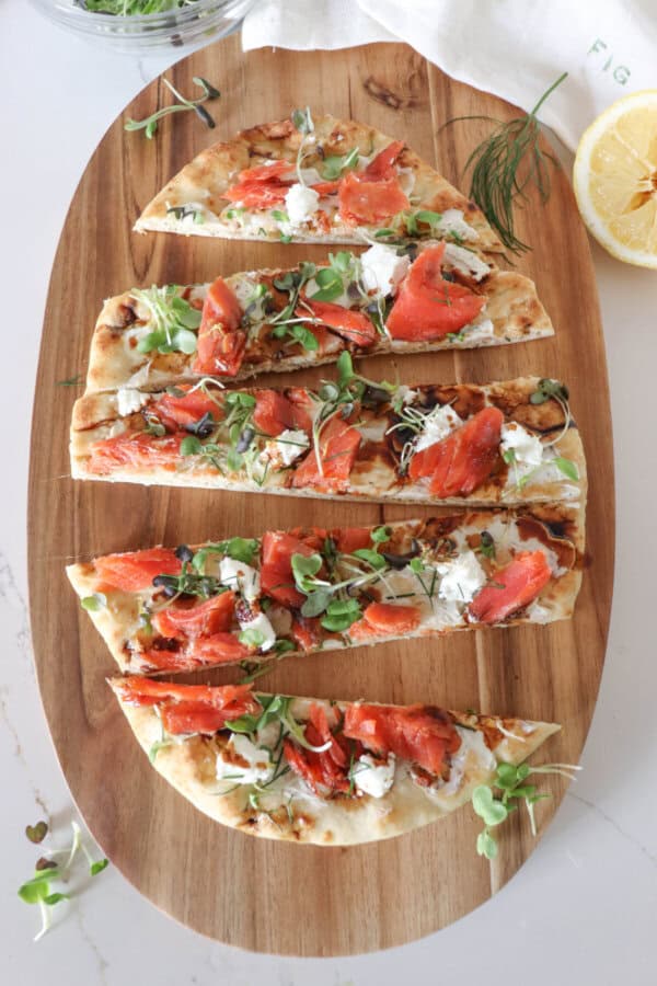 Flatbread topped with cream cheese, smoked salmon pieces, mustard greens, crumbled goat cheese and drizzled with balsamic vinegar cut into 1" strips.