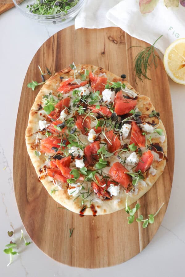 Flatbread topped with cream cheese, smoked salmon pieces, mustard greens, crumbled goat cheese and drizzled with balsamic vinegar.