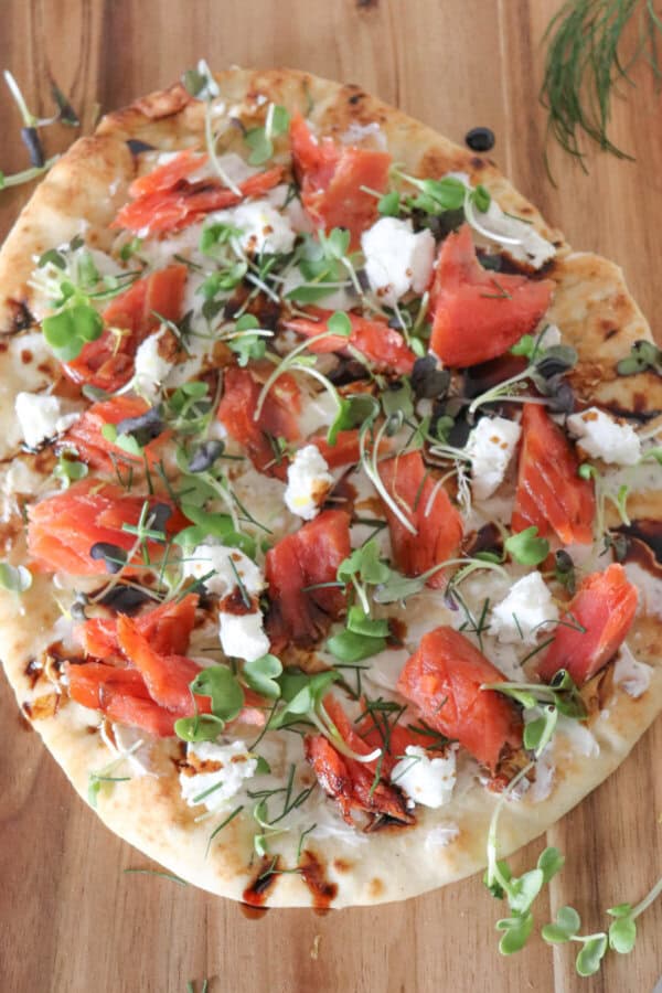 Flatbread topped with cream cheese, smoked salmon pieces, mustard greens, crumbled goat cheese and drizzled with balsamic vinegar.