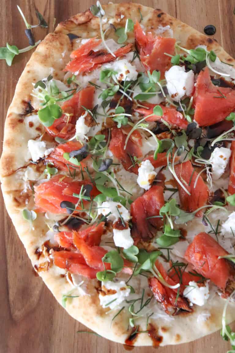 Flatbread topped with cream cheese, smoked salmon pieces, mustard greens, crumbled goat cheese and drizzled with balsamic vinegar.