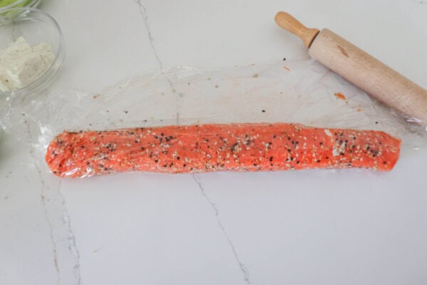 Smoked salmon rolled into a log on a white counter.