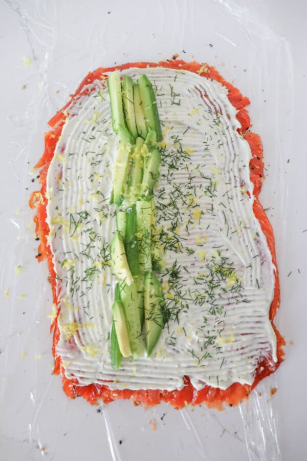 Smoke salmon flattened and covered in cream cheese with avocado and cucumber spears down the center, sprinkled with dill and lemon zest.