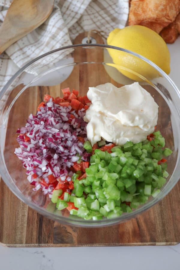 Ingredients for smoked salmon salad in a clear glass bowl.