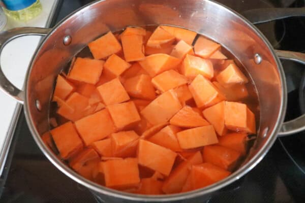 Sweet potatoes cubed in water in a pot on the stove.