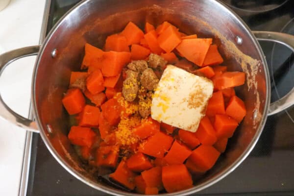 Sweet potato cubes with butter and brown sugar in a large pot.