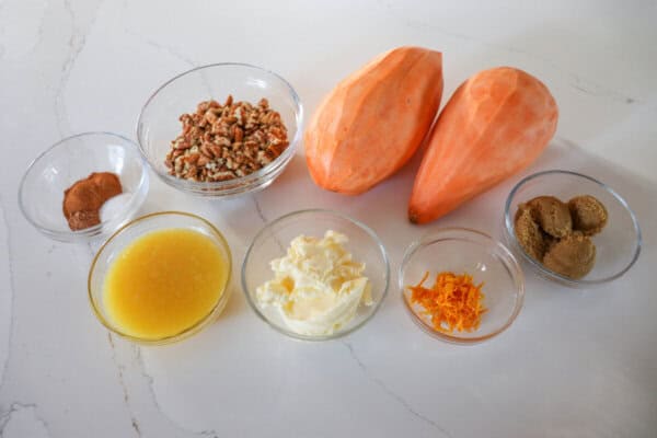 Sweet potato casserole ingredients in clear glass bowls on a white counter.