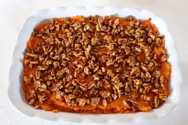 Mashed sweet potatoes topped with pecan streusel in a large white casserole dish.