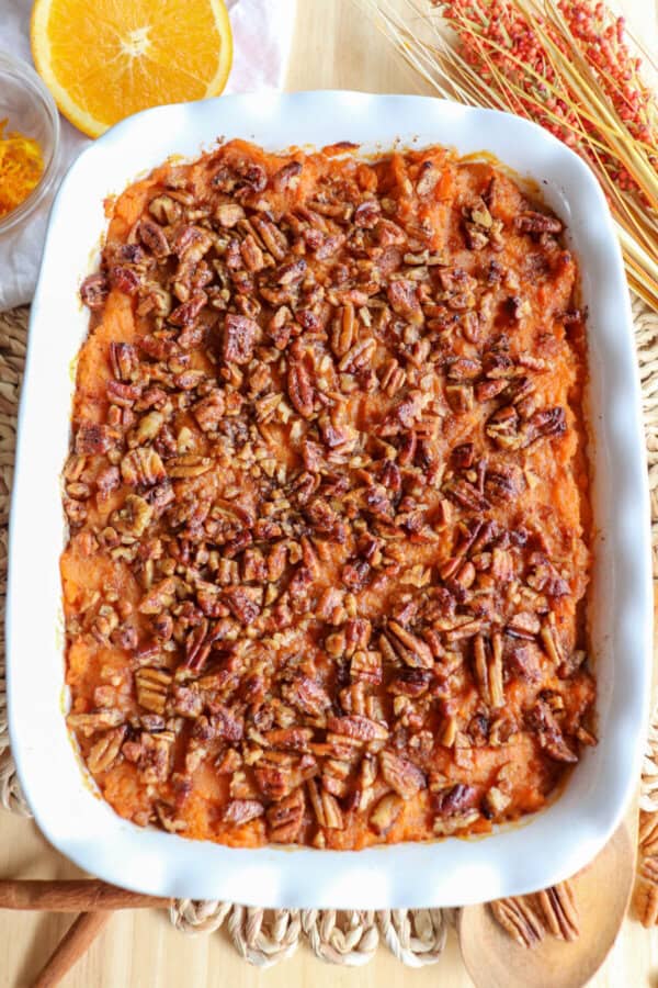 Sweet potato casserole topped with a caramel pecan streusel in a white casserole dish.