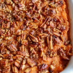 Sweet potato casserole topped with a caramel pecan streusel in a white casserole dish.
