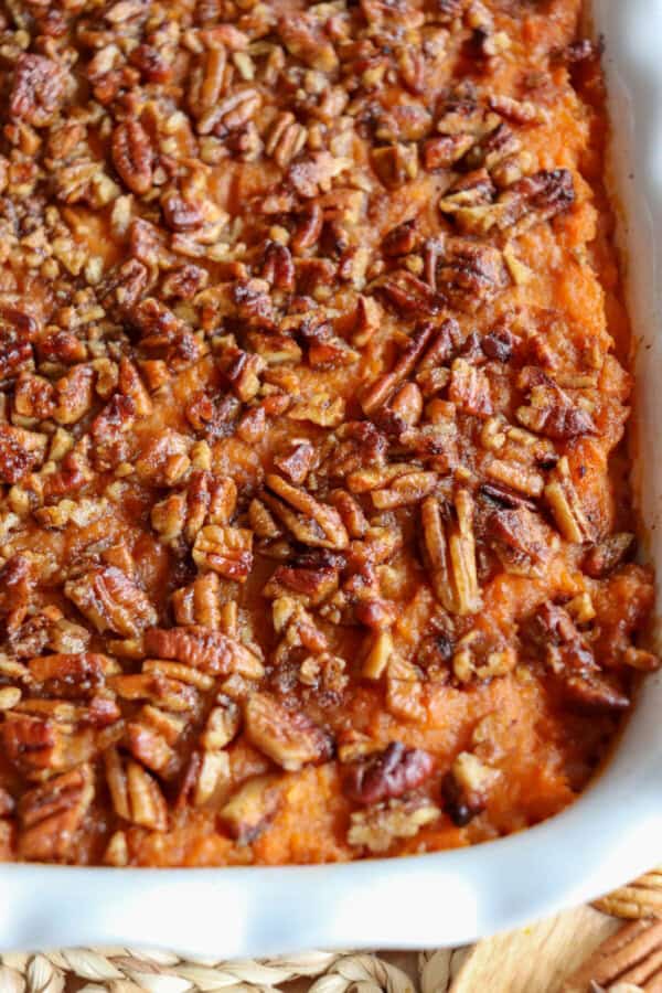 Sweet potato casserole topped with a caramel pecan streusel in a white casserole dish.