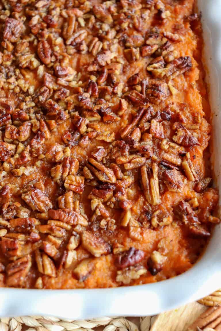 Sweet potato casserole topped with a caramel pecan streusel in a white casserole dish.