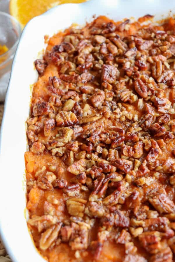 Sweet potato casserole topped with a caramel pecan streusel in a white casserole dish.