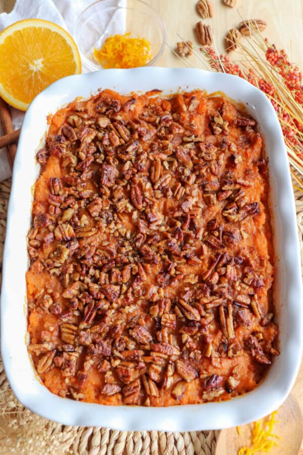 Sweet potato casserole topped with a caramel pecan streusel in a white casserole dish.