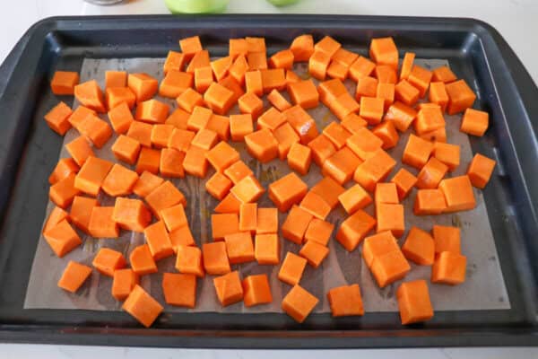 Sweet potato cubes on a parchment paper lined baking sheet.