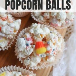 Popcorn balls with Halloween sprinkles and candy corn in cupcake liners on a wooden cutting board.