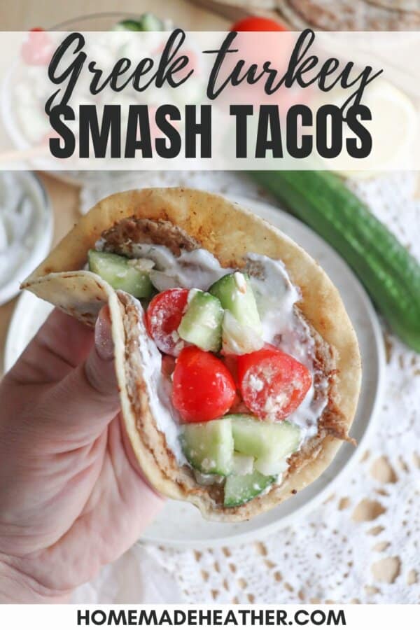 Tortilla with cooked ground turkey, diced cucumber, tomato and tzatziki sauce held in a hand.
