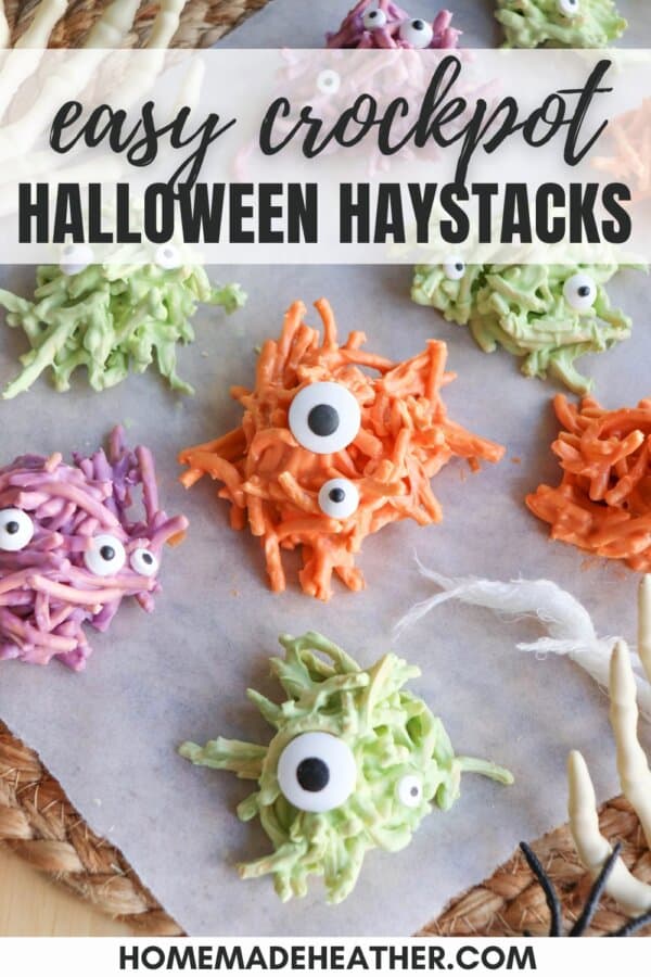Colorful chocolate covered haystacks with candy eyes on a sheet of parchment paper.