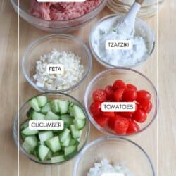 Ingredients for turkey smash tacos in clear glass bowls on a wooden table.