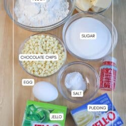 Ingredients for grinch pudding cookies in clear glass bowls on a wooden table.