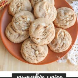 Caramel colored pumpkin spice cookies with white chocolate chips stacked on an orange plate.