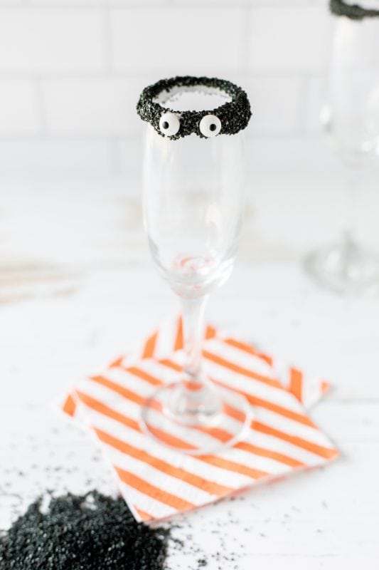 Champagne glass with black frosting rim and candy eyes.