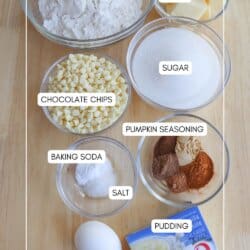 Pumpkin spice pudding cookie ingredients in clear glass bowls on a wooden table.