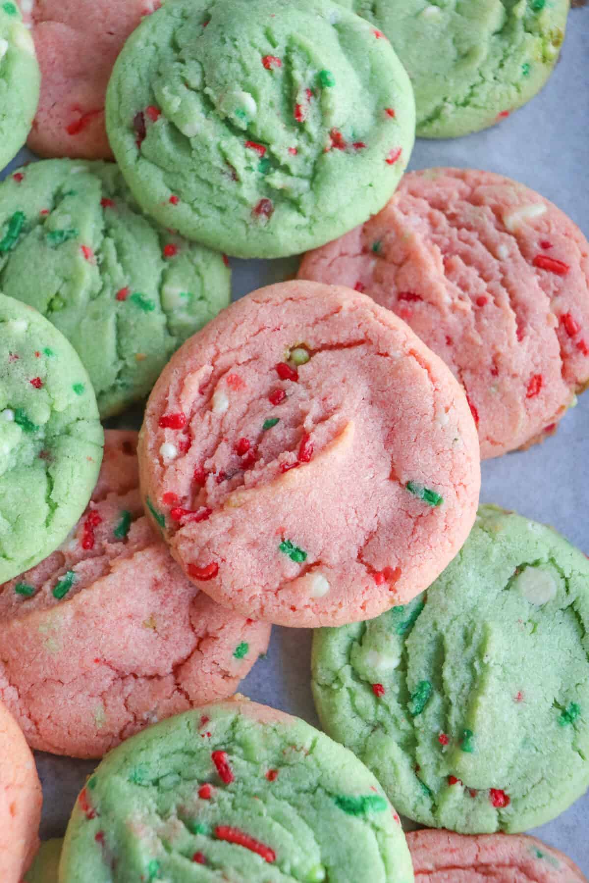 Pink and green cookies with Christmas sprinkles stacked on top of one another.