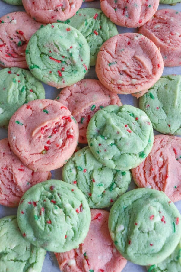 Pink and green cookies with Christmas sprinkles stacked on top of one another.