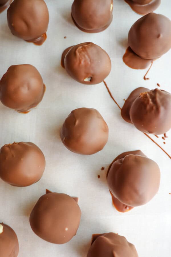 Cottage cheese protein cookie dough balls covered in chocolate on a piece of parchment paper.