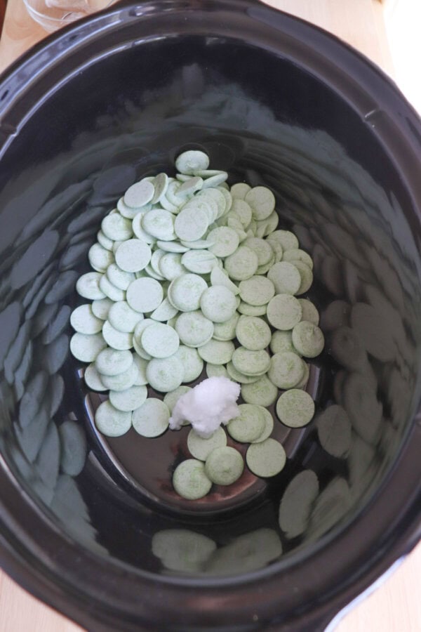 Green candy melts in a large black crock pot.
