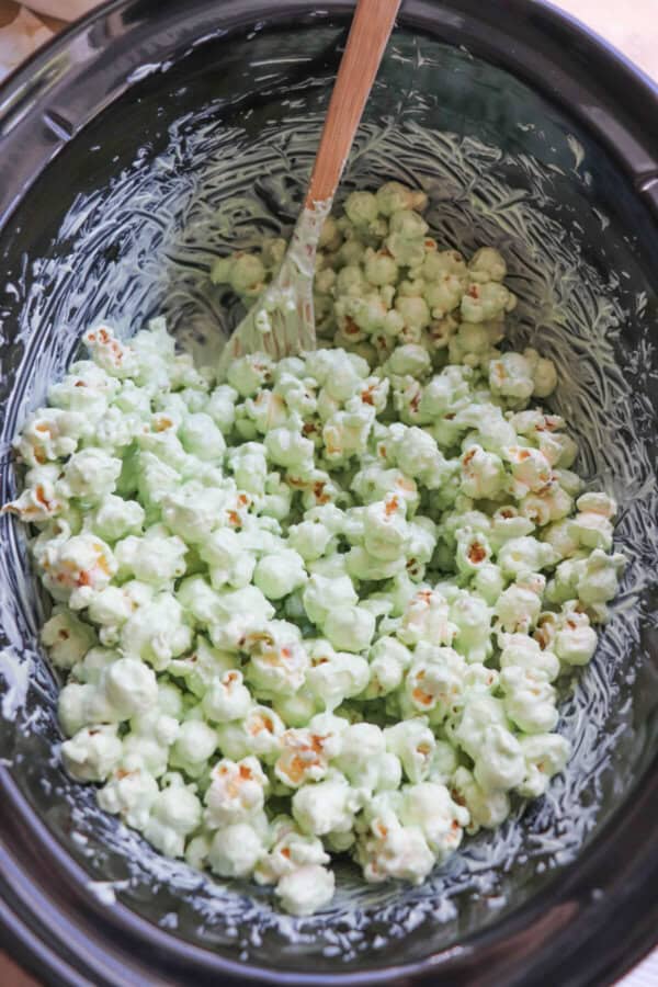 Popcorn coated in green chocolate in a black crockpot.