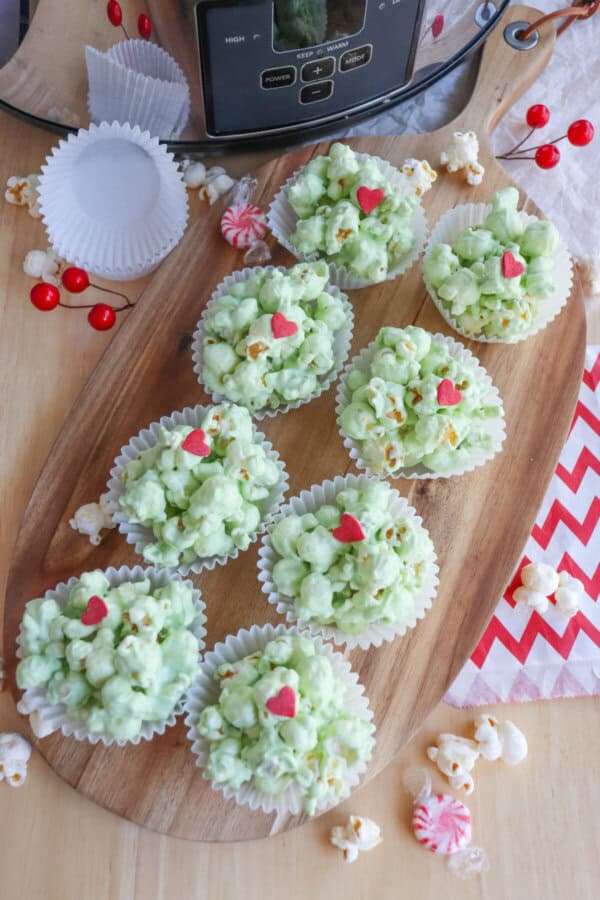 Green popcorn balls in white cupcake liners topped with a red candy heart.