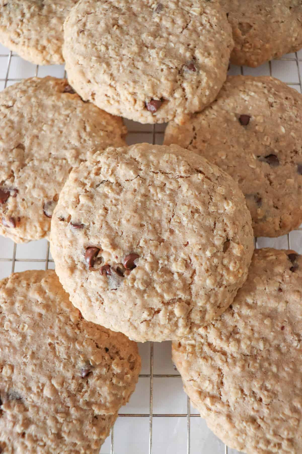 Large oatmeal chocolate chip cookies stacked on one another.