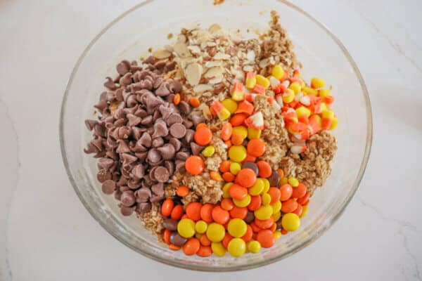 Ingredients for Halloween kitchen sink cookies in a medium clear glass mixing bowl.