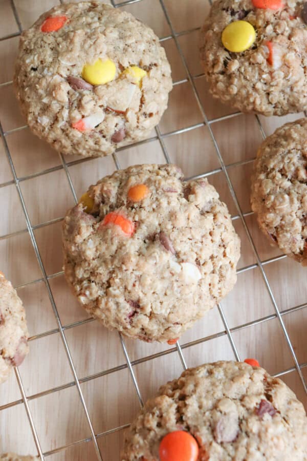 Oatmeal chocolate chip cookies with Halloween candy on a wire rack.